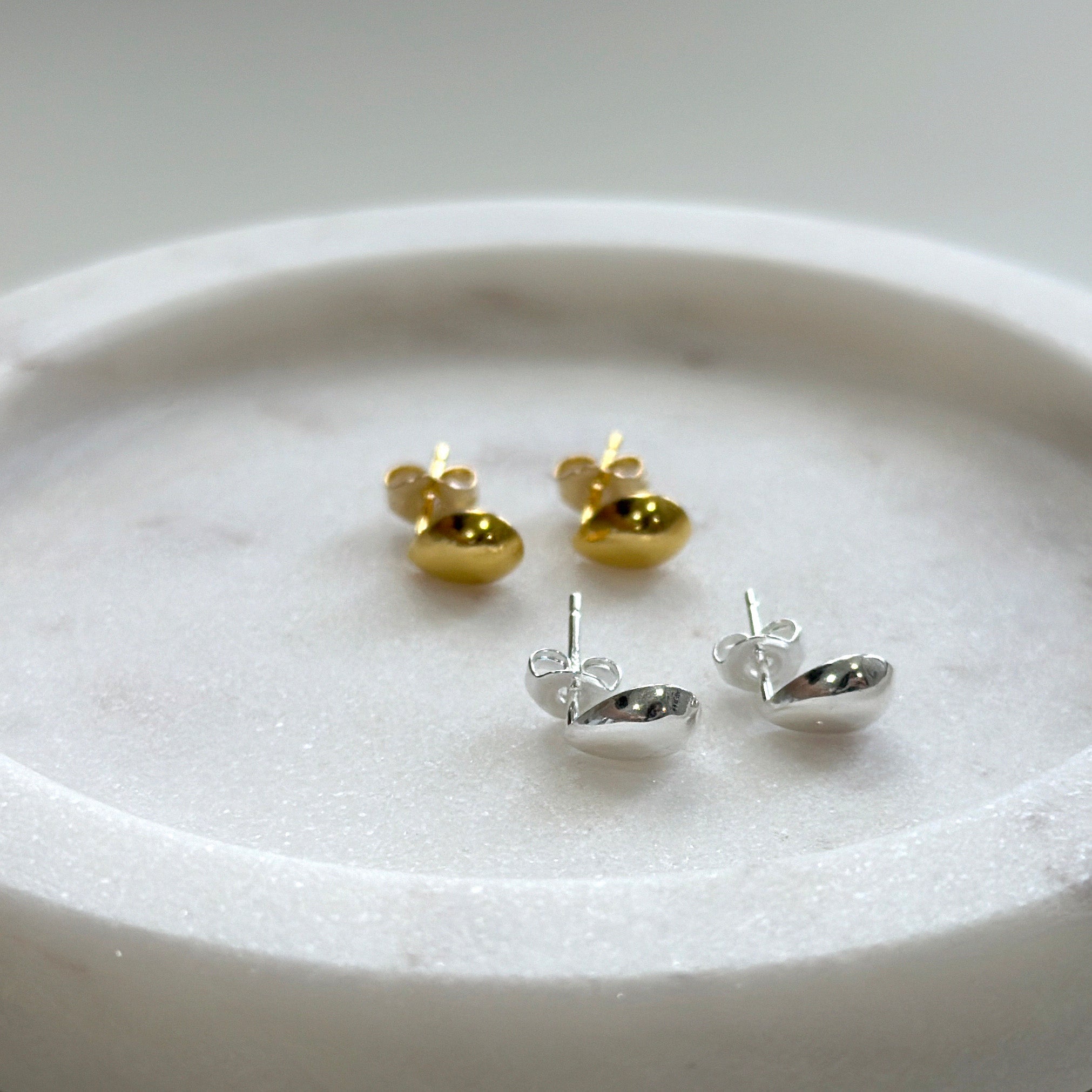 Gold and silver Teardrop-shaped earrings on a white plate