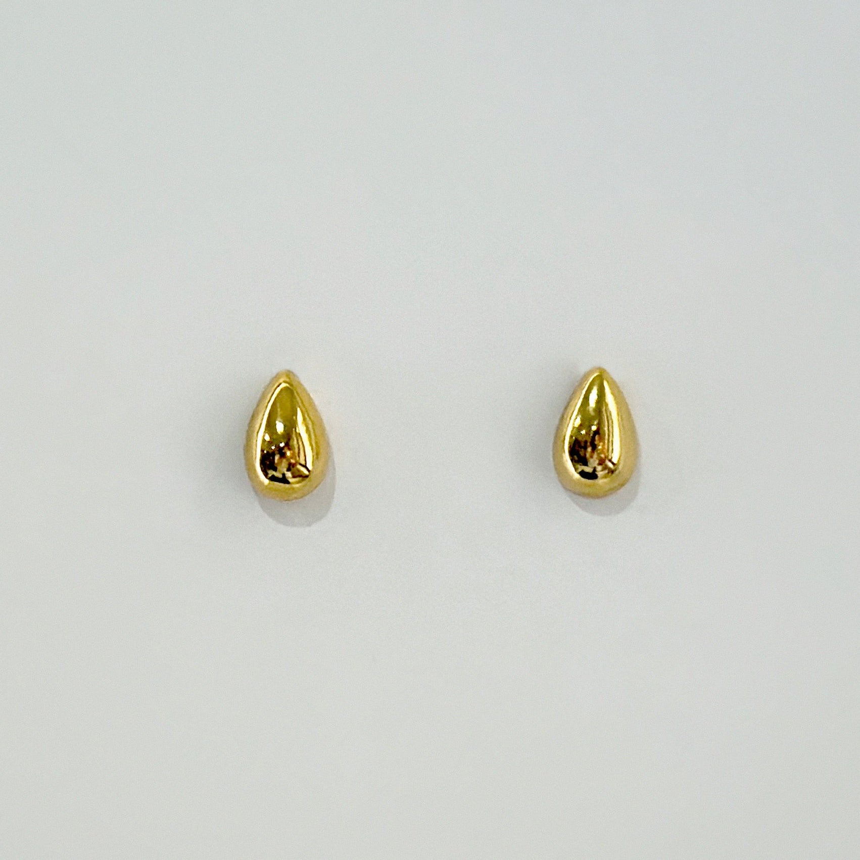 Gold teardrop earrings on a light gray background