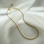 Vienna Necklace styled on a beige linen surface with soft shadows enhancing its shine