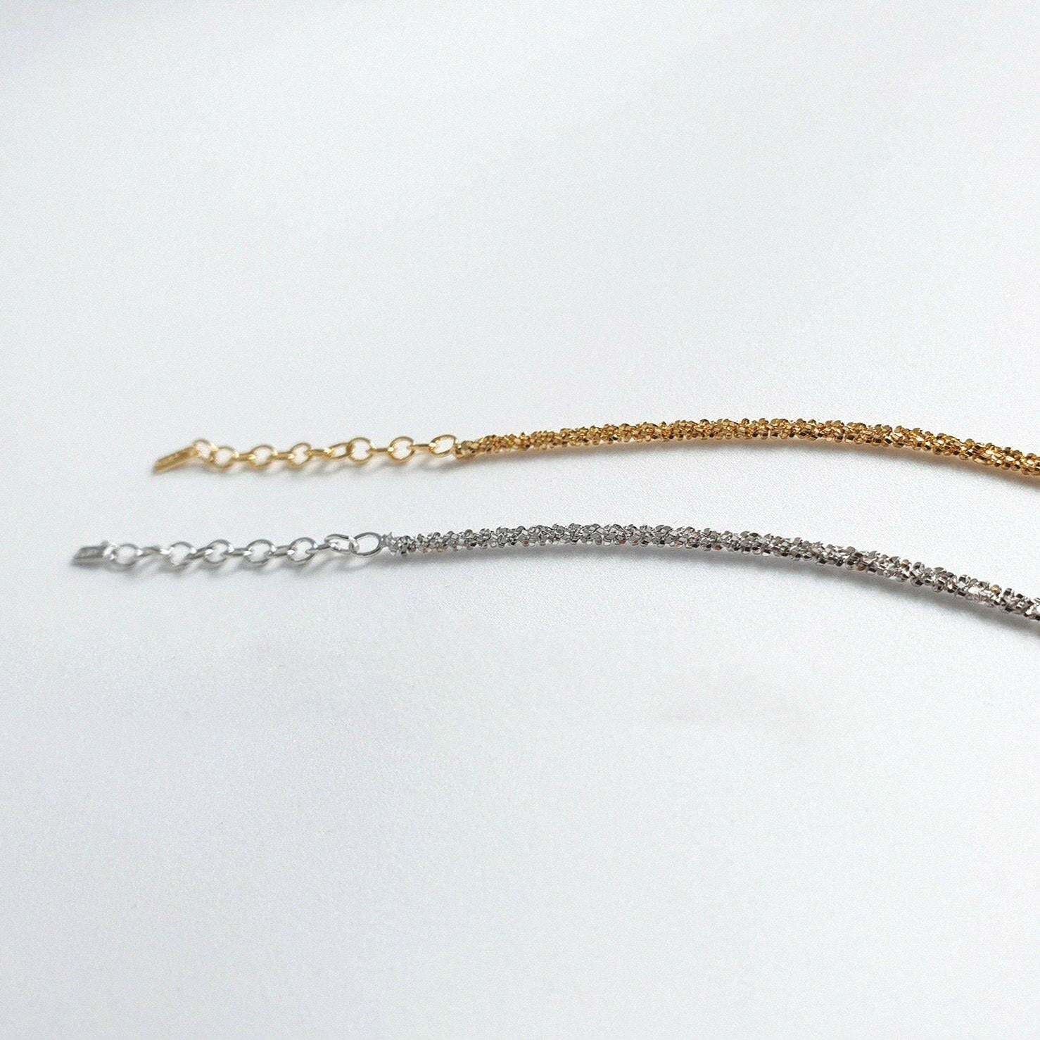 Two gold and silver bracelets on a white background