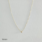 Gold necklace with a small round pendant on a light gray background