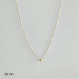Gold necklace with a small round pendant on a light gray background