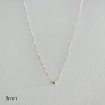 Gold necklace with a small round pendant on a light gray background