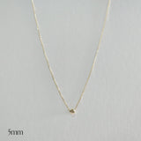 Gold necklace with a small round pendant on a light gray background