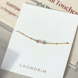 Gold bracelet with multicolored beads on a white card with 'LAONDRIM' branding.