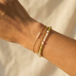 Close-up of a wrist wearing two beaded bracelets on a neutral background