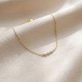 Gold necklace with pearls on a white surface