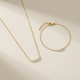 Gold necklace and bracelet set on a beige background