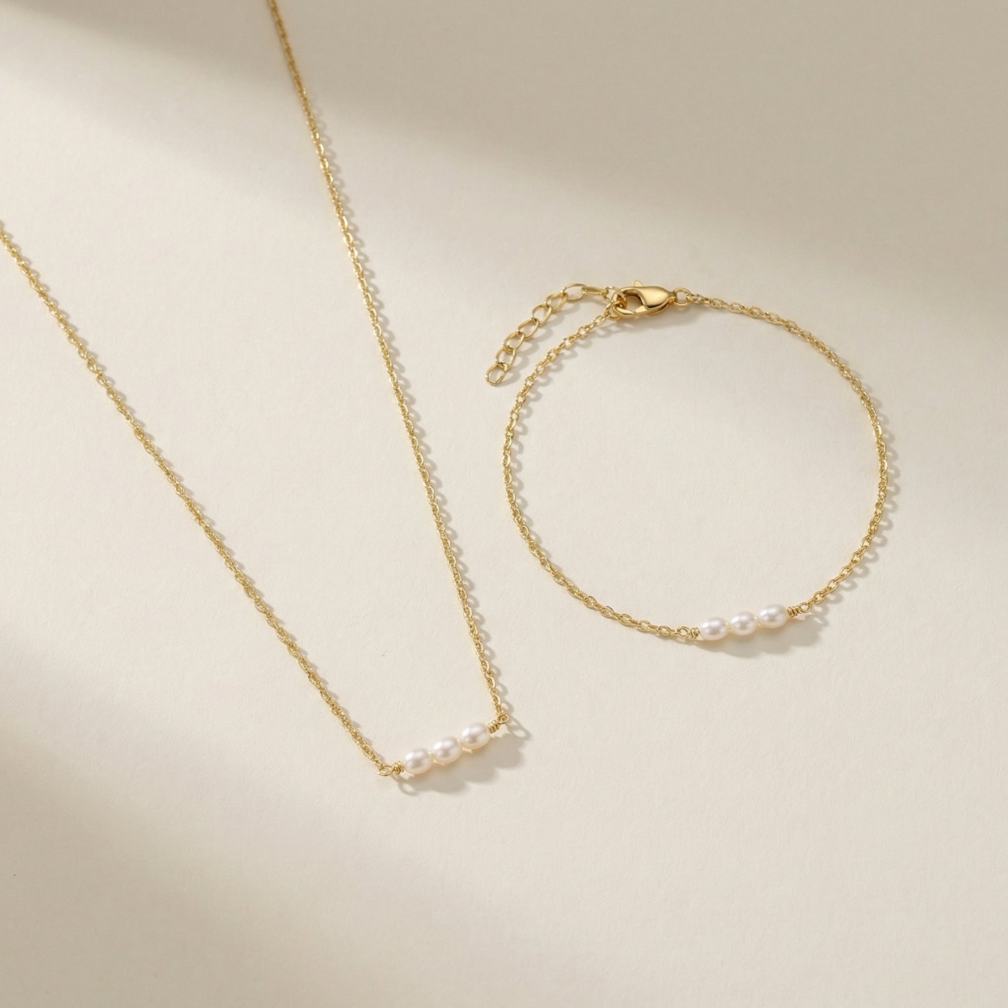 Gold necklace and bracelet set on a beige background