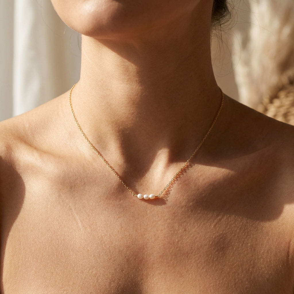 Close-up of a person wearing a delicate necklace with small pearls.