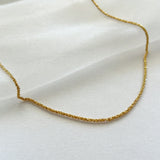 Close-up of sterling gold basa necklace on shimmery soft fabric