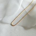 Gold Basa chain styled on shimmery fabric with soft natural lighting.