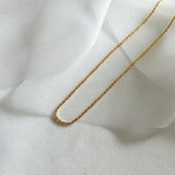 Gold Basa chain styled on shimmery fabric with soft natural lighting.