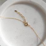 Gold necklace chain with spring ring claps and extension chain on a marble surface