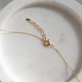 Gold necklace chain with spring ring claps and extension chain on a marble surface