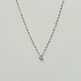 Delicate twisted chain necklace with cubic zirconia centerpiece on a neutral background