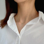 Model wearing 10mm clover pendant necklace in gold with open neckline