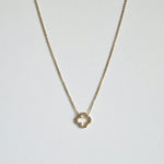 Crystal clover gold necklace  with sparkling pendant laid flat in a soft curve