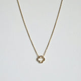 Crystal clover gold necklace  with sparkling pendant laid flat in a soft curve