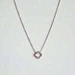 Crystal clover silver necklace  with sparkling pendant laid flat in a soft curve