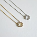 Gold and silver clover necklaces displayed side by side with cubic zirconia accents