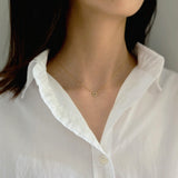 Model wearing small clover necklace in gold as a subtle daily accessory