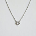 Close-up highlighting the four-leaf shape and crystal sparkle with dainty chain