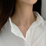 Model wearing dainty crystal cross necklace as an everyday statement