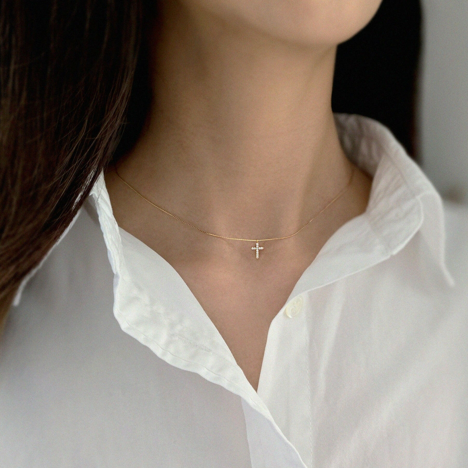 Model wearing dainty crystal cross necklace as an everyday statement
