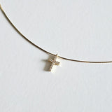 Close-up of cubic zirconia cross on fine gold snake chain with polished finish