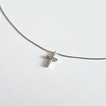 Close-up of cubic zirconia cross on fine silver snake chain with polished finish