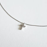 Close-up of cubic zirconia cross on fine silver snake chain with polished finish