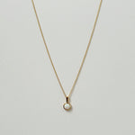 Opal pendant necklace laid flat, featuring a luminous round white opal on a gold chain