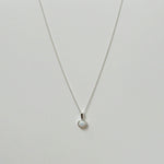 Opal pendant necklace laid flat, featuring a luminous round white opal on a silver chain