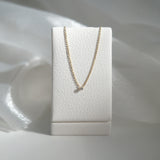 Gold necklace on a white jewelry display box against a soft white background
