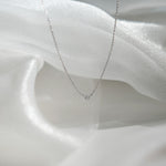 Silver necklace with a small diamond pendant on a white fabric background