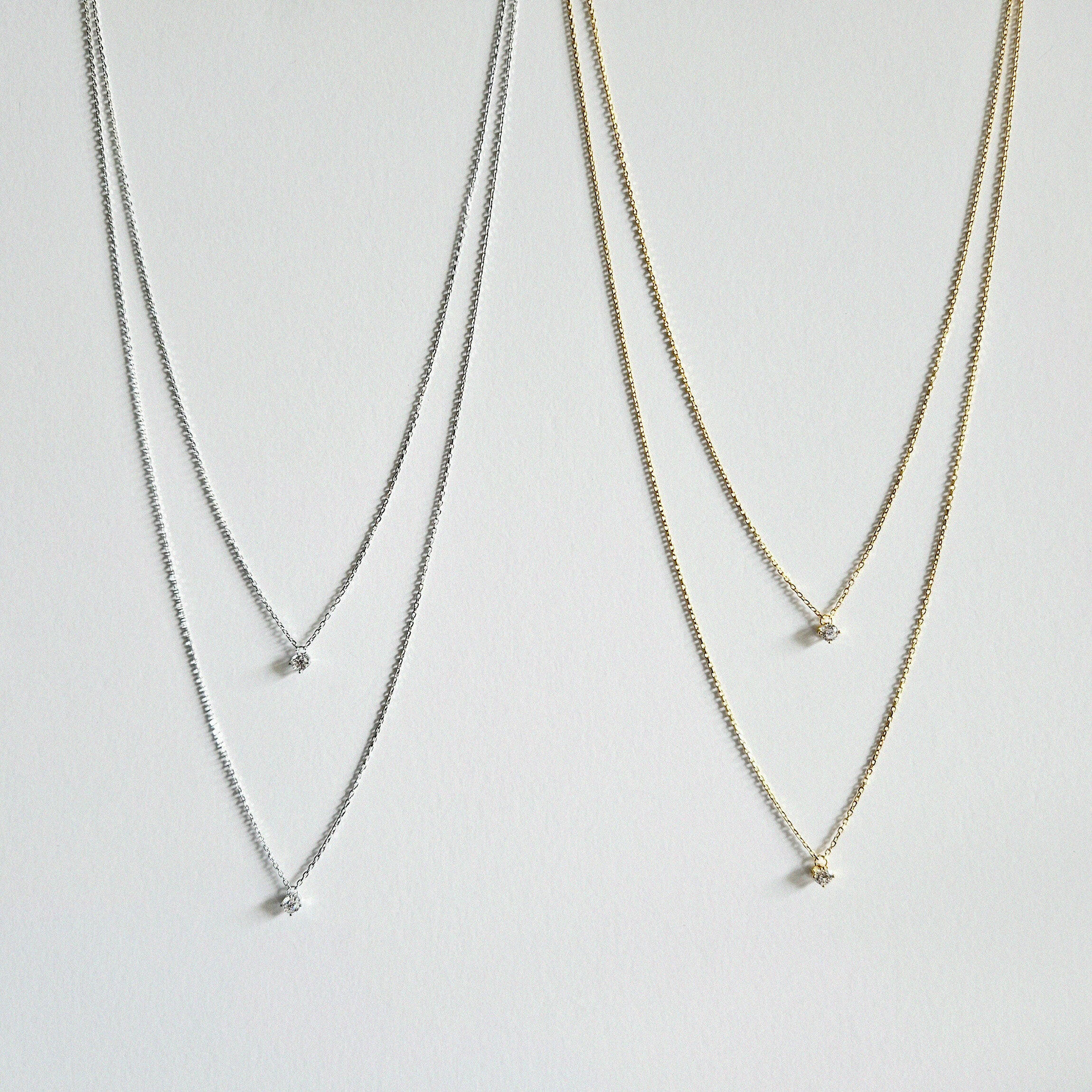 Gold and silver double chain necklaces laid flat showing cubic zirconia placement