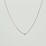 Petite crystal snake chain necklace in gold  laid flat in a delicate curve with cubic zirconia accent.