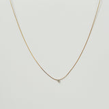 Petite crystal snake chain necklace in gold  laid flat in a delicate curve with cubic zirconia accent.