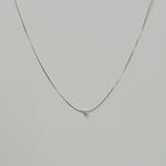 Petite crystal snake chain necklace in silver laid flat in a delicate curve with cubic zirconia accent.