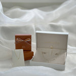 Jewelry set with necklace and earrings in an open box on a white fabric background