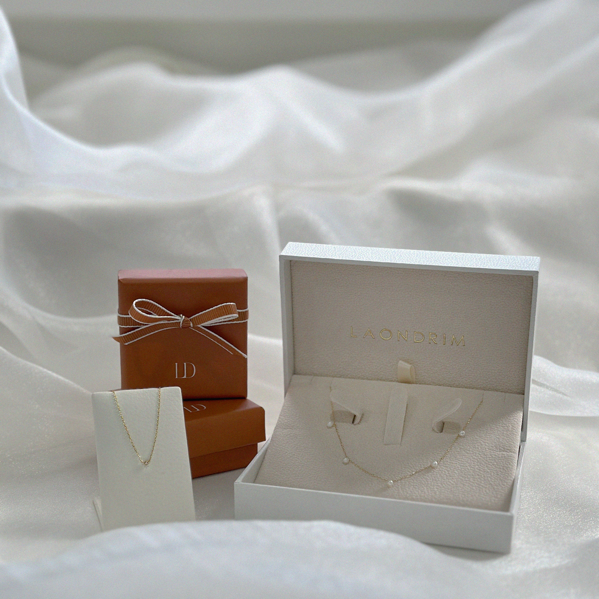 Jewelry set with necklace and earrings in an open box on a white fabric background