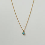 Delicate circular blue opal necklaces arranged in a minimal flat lay