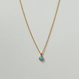 Delicate circular blue opal necklaces arranged in a minimal flat lay