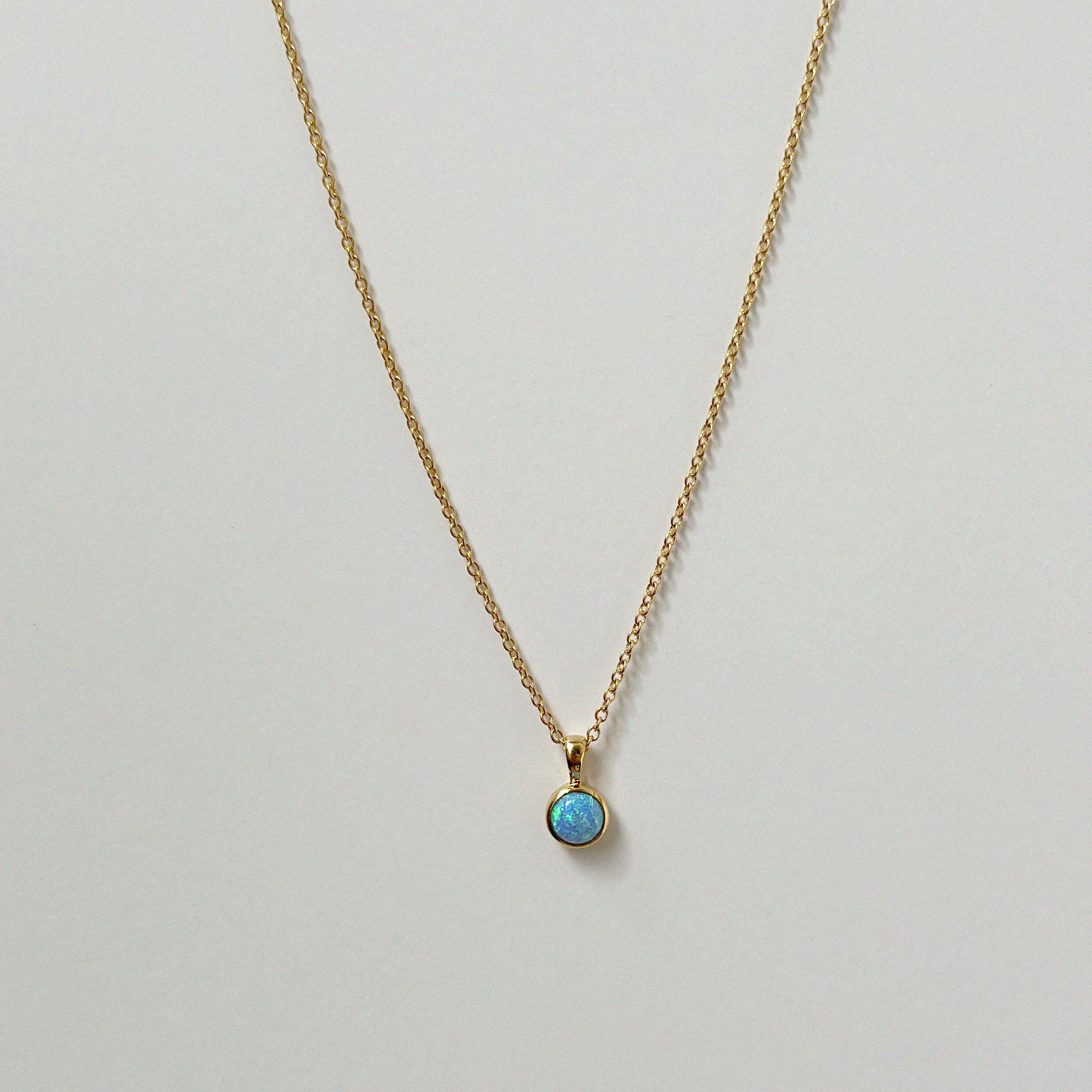 Delicate circular blue opal necklaces arranged in a minimal flat lay