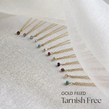 Gold filled necklaces with gemstones on a white fabric background