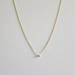 Gold necklace with a small cubic zirconia pendant on a light gray background