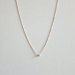 Silver necklace with a small round cubic zirconia pendant on a light gray background