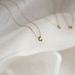 Gold necklace with a crescent moon pendant on a white fabric background