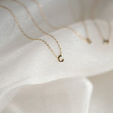 Gold necklace with a crescent moon pendant on a white fabric background